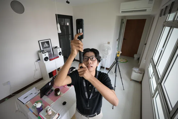 Research assistant Khant Min Naing from SUTD’s Lee Kuan Yew Centre for Innovative Cities taking photos of a resident’s home with a 360-degree camera, 21 February 2025. 