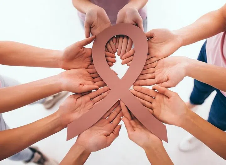 Cropped image of group of young multiracial woman holding pink ribbons in hands. Struggling against breast cancer. Breast cancer awareness concept.