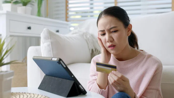 Upset young asia teen girl sit at home sofa couch feel shock broke doubt annoy or lost money in e-commerce app error buy issue, wrong hoax digital wallet hacked or bad theft steal crime fraud banking.