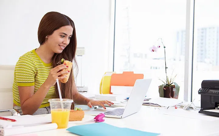 Woman Working In Design Studio Having Lunch At Desk