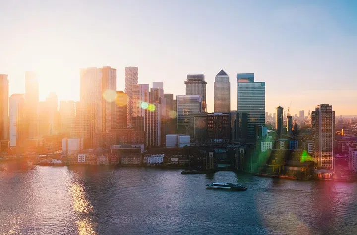 UK, London, elevated view over city financial district skyline of Canary Wharf illuminated at sunset