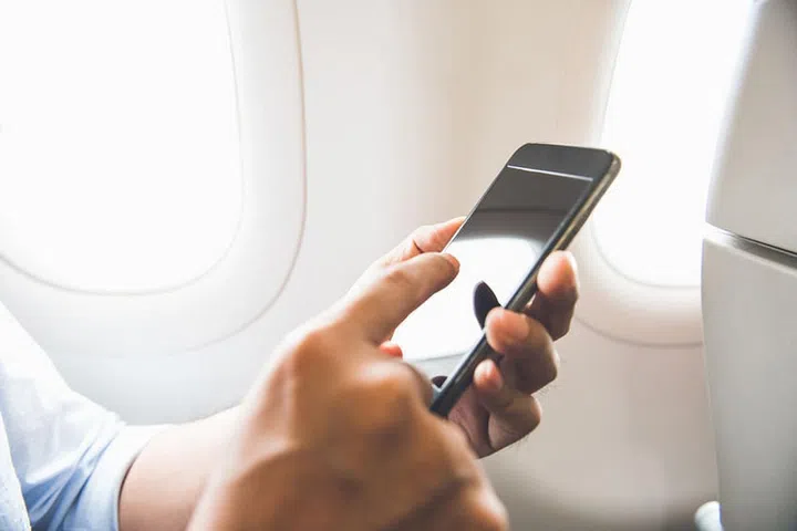 Male passenger using mobile phone on the airplane while traveling