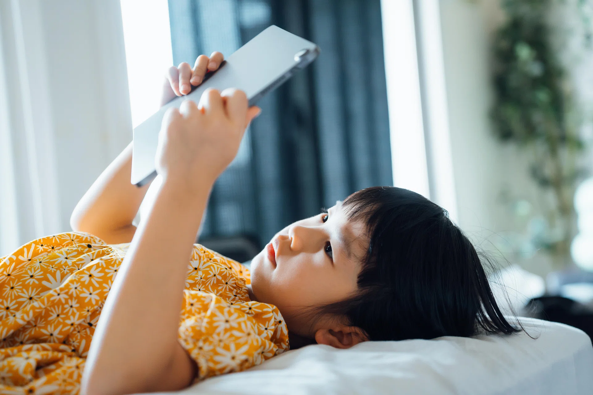 Girl lying down on bed using ipad