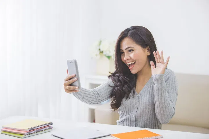 portrait of asian woman at home making a video call using smart phone