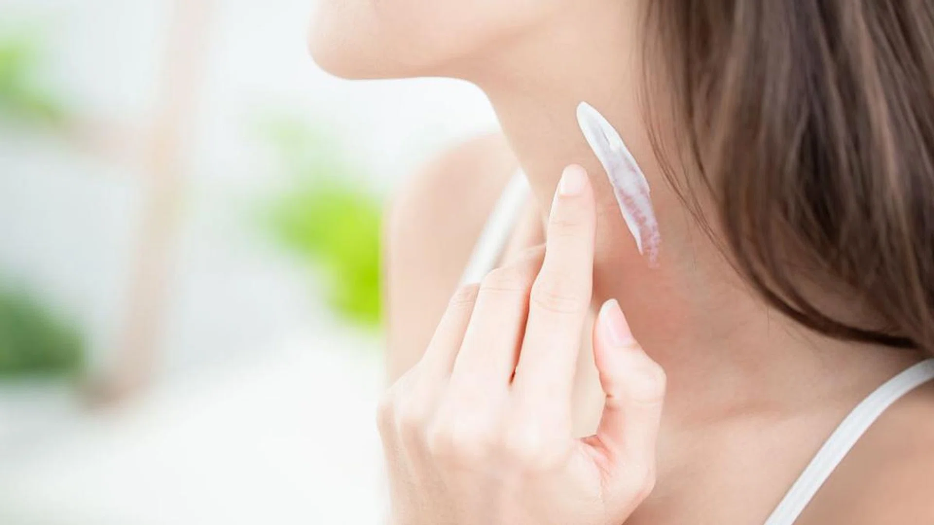 woman applying sunscreen on her neck