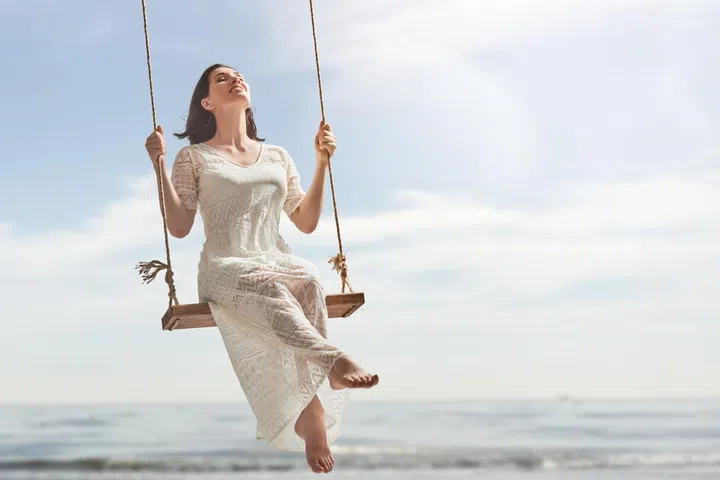 beautiful young woman on a swing on summer day outdoors