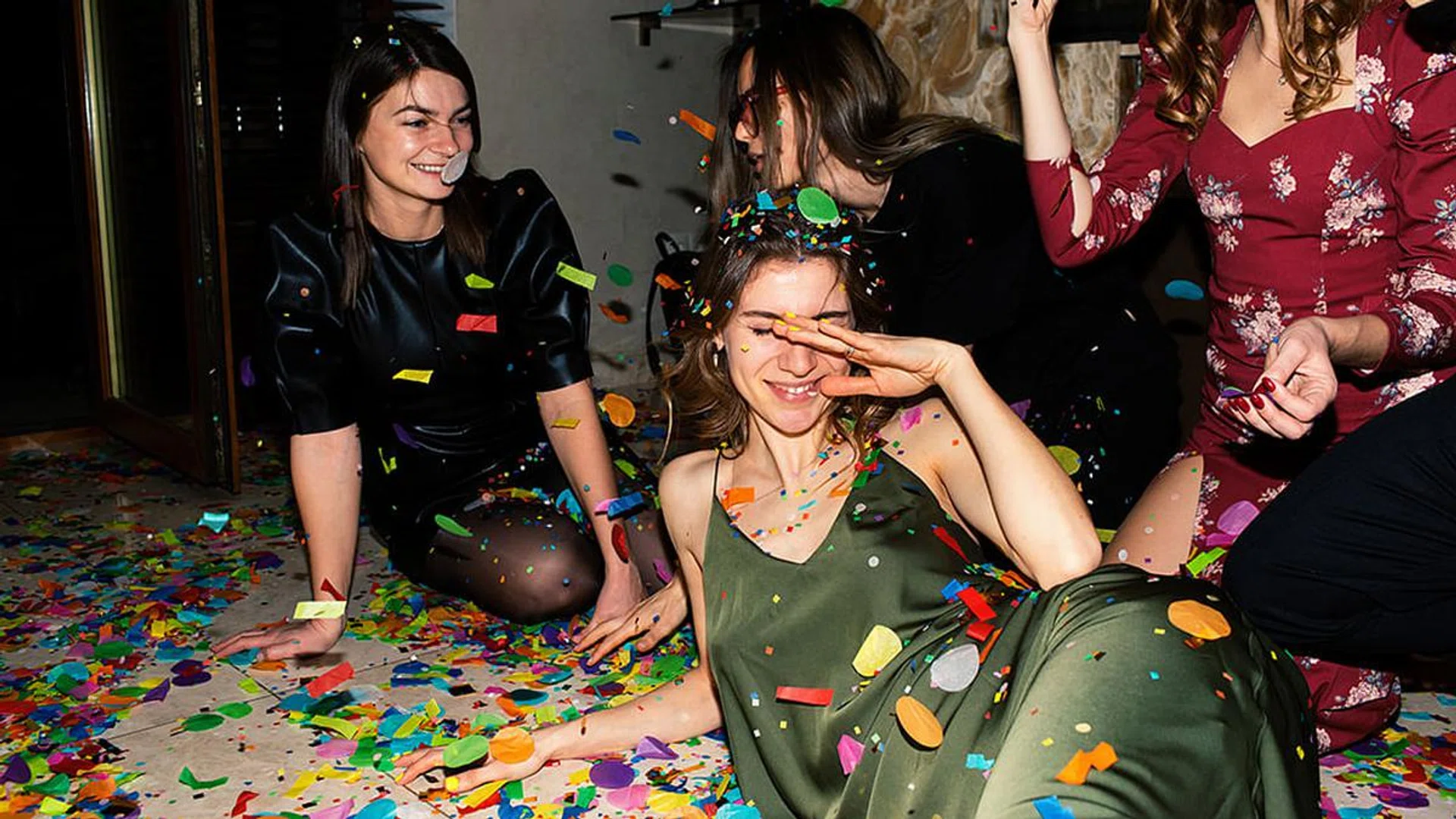Group of beautiful young people throwing colorful confetti while dancing and looking happy. Friends making big party in the night. New year's or Birthday party. Series.