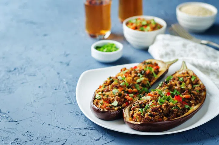 Minced meat quinoa vegetables stuffed eggplants on a stone background. toning. selective focus