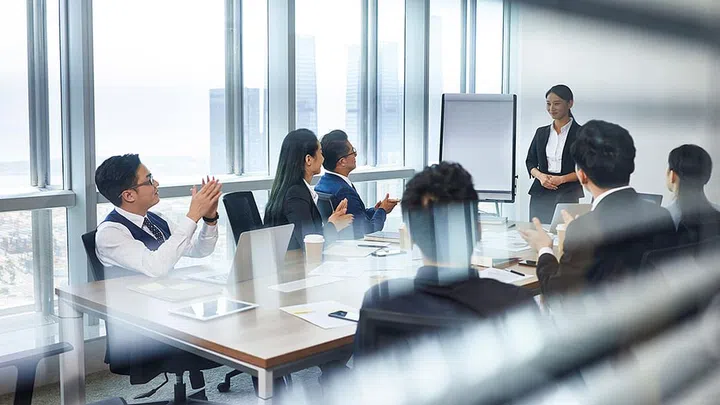 asian new employee introducing self during staff meeting in conference room