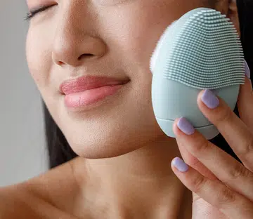 Woman using a skincare device for glowing, youthful skin at home