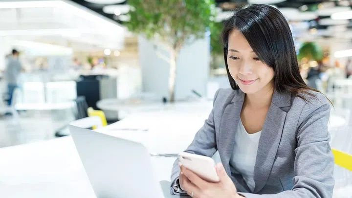 Businesswoman checking on cellphone and use of laptop computer