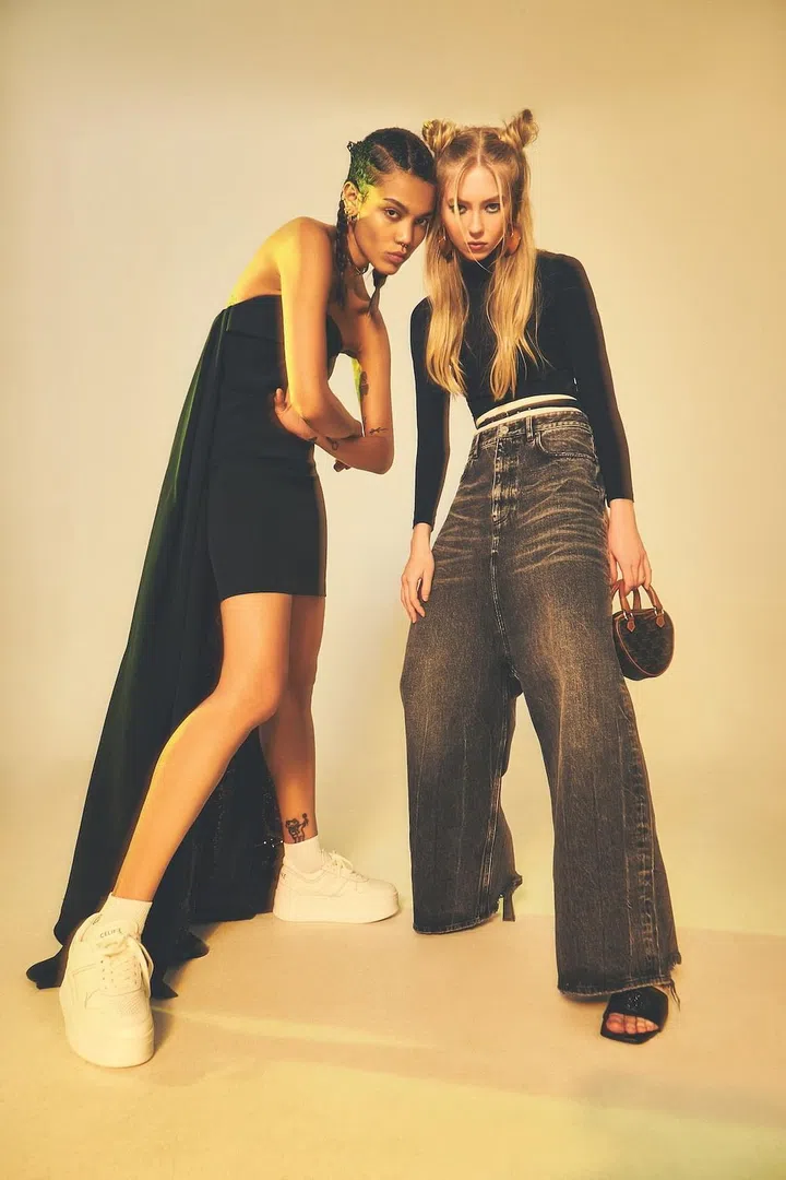 On Noelle (left): Strapless mini dress with attached train and calfskin sneakers, Celine. Socks, stylist’s own

On Belinda (right): Cotton turtleneck top and denim oversized jeans, Balenciaga. High-waisted underwear, Max Mara. Skinny leather belt and oversized gold-tone disc earrings, Fendi. Monogram top-handle heart  purse, Celine. Leather slip-ons, Versace