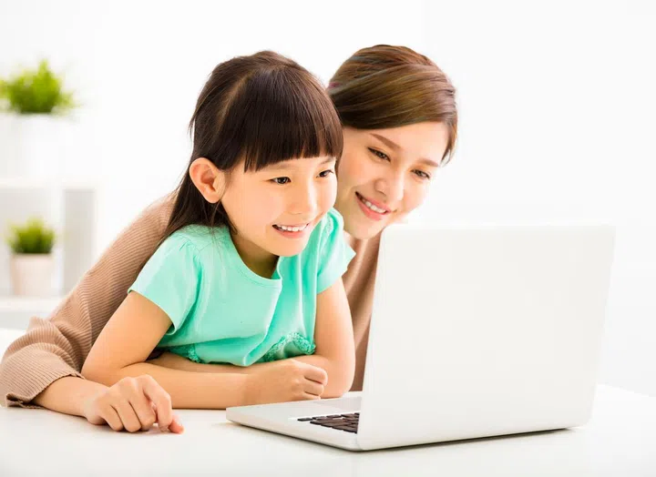 happy Little girl looking at laptop  with her mother