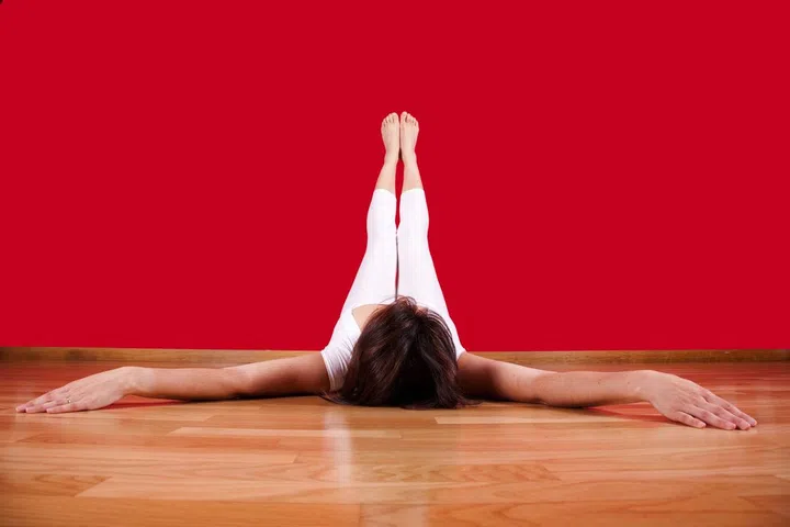 woman laying on the floor of her house with her legs up next to a red wall