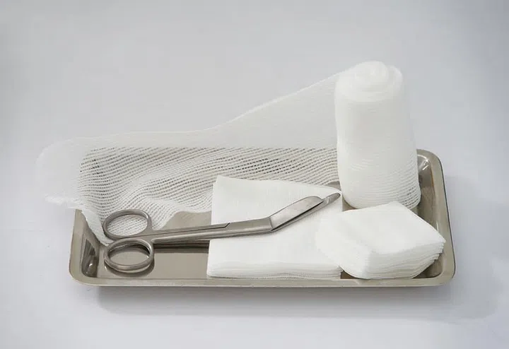 roll and pad gauze with scissors on tray for dressing wound on isolated white background