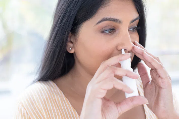 Woman using a nasal spray.