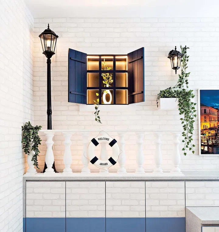 The living area features a canal-like setting with the television feature wall mimicking the banks of a canal, complete with decorative rails, windows, and a streetlamp, as well as carpentry with a blue strip to symbolise the waterline.