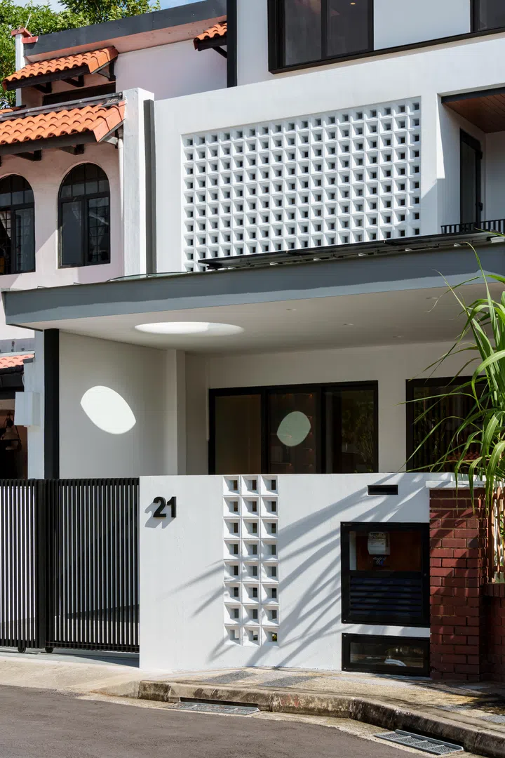 The extended car porch roof solves a practical weather issue, while a circular skylight opening keeps the sheltered entrance bright and visually connected to the sky.