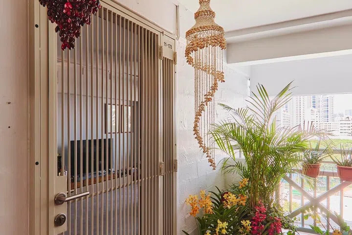 Orchids, hanging beadwork and potted greenery create a warm welcome outside the flat, offering a glimpse of the collected, garden-inspired world within.