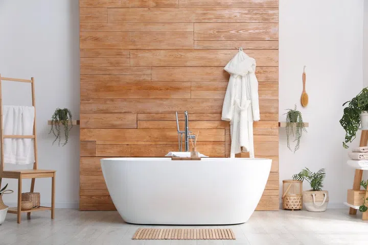 Stylish bathroom interior with modern bathtub and towel on wooden wall.