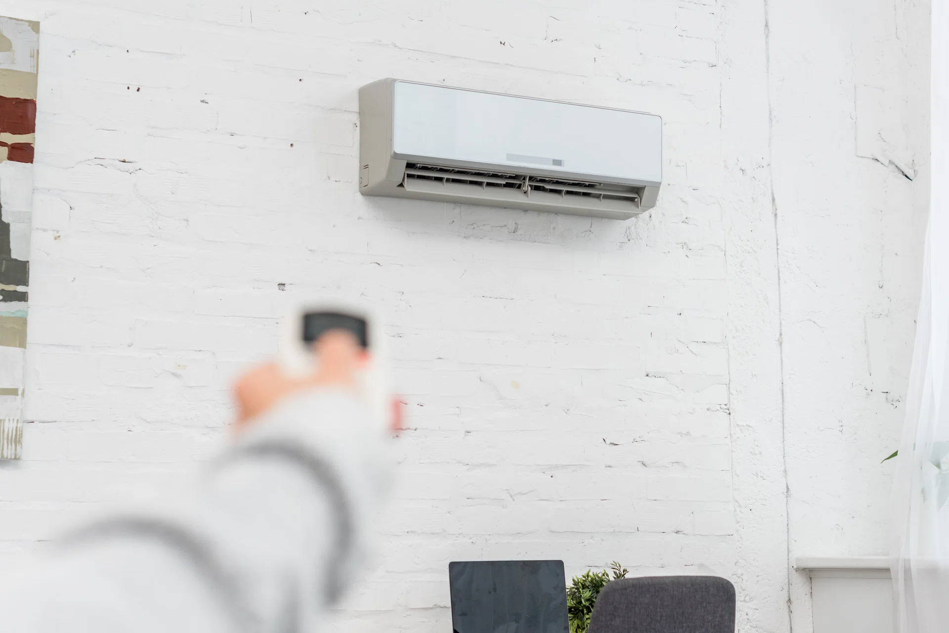 cropped shot of woman pointing at air conditioner with remote control