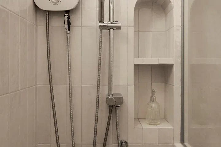 An arched shower niche echoes the home’s recurring curved motifs while providing practicality.