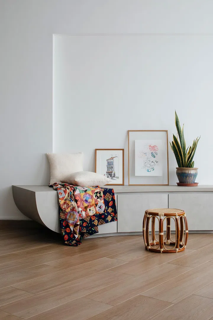 Storage, seating, display — the curved frame offers a myriad of options. The space is furnished with pictures, plants, and wooden stools that are all gifts from friends.