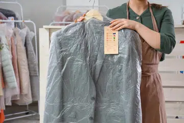 Young female worker with suit at dry-cleaner’s.