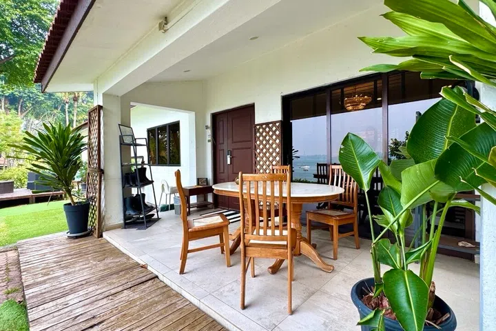 Lush outdoor foliage sets a tropical colonial tone, while the shaded porch seating area offers a cozy, up-close spot to soak in the sea view. Note the boot rack by the entrance!