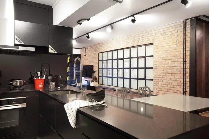 Bridging the dining and living area is a feature wall inspired by the urban industrial interiors of New York lofts. Interior design by Space Sense