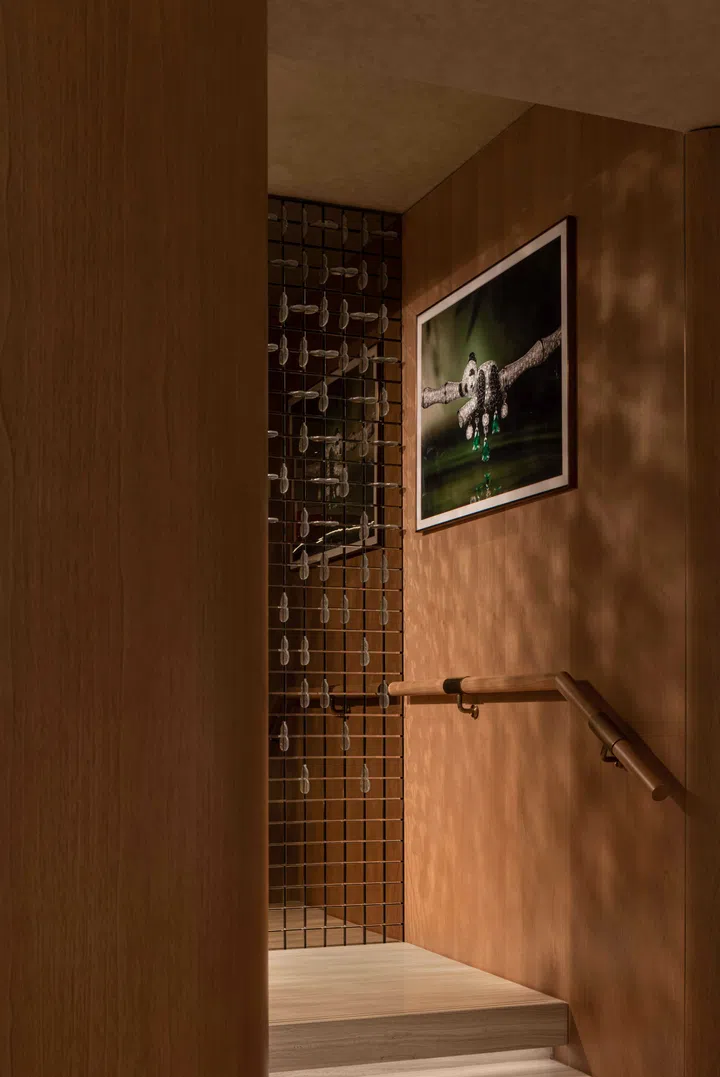 Daylight enters through a linear skylight layered with a delicate lattice of repeated Wulu (gourd-shaped) motifs, casting shifting shadows along the walkway. Jewellery display cases feature a bespoke red-to-black lacquer gradient finish.