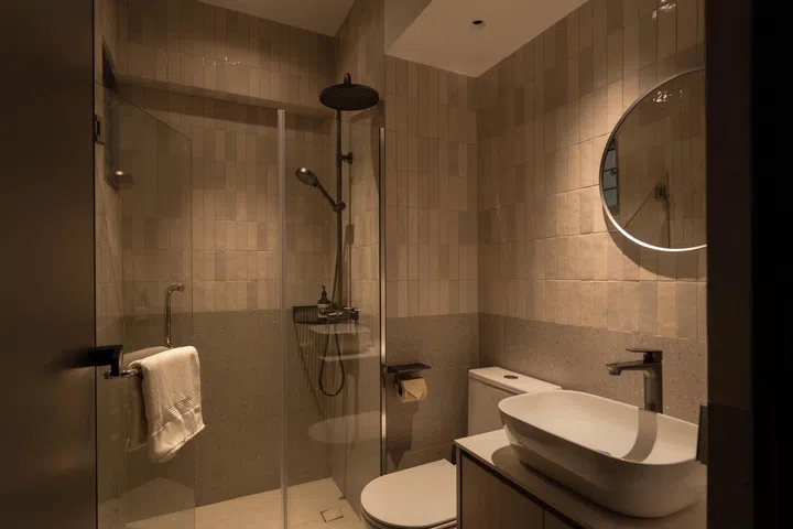  In contrast, the lighter common bathroom uses pale tiles and soft lighting for a spa-like openness.
