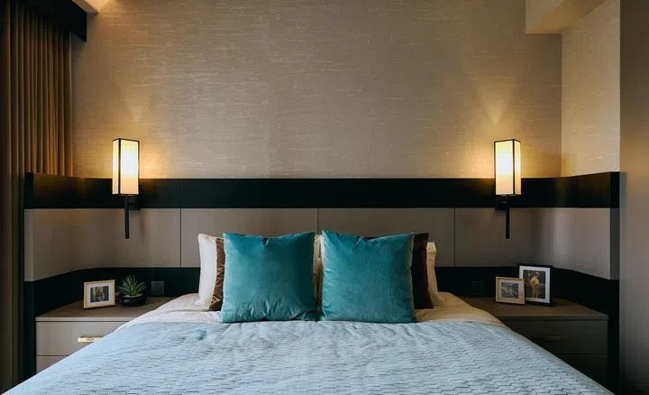 A linear headboard framed by Oriental wall lamps, textured wallcoverings, and green accents create a serene retreat.
