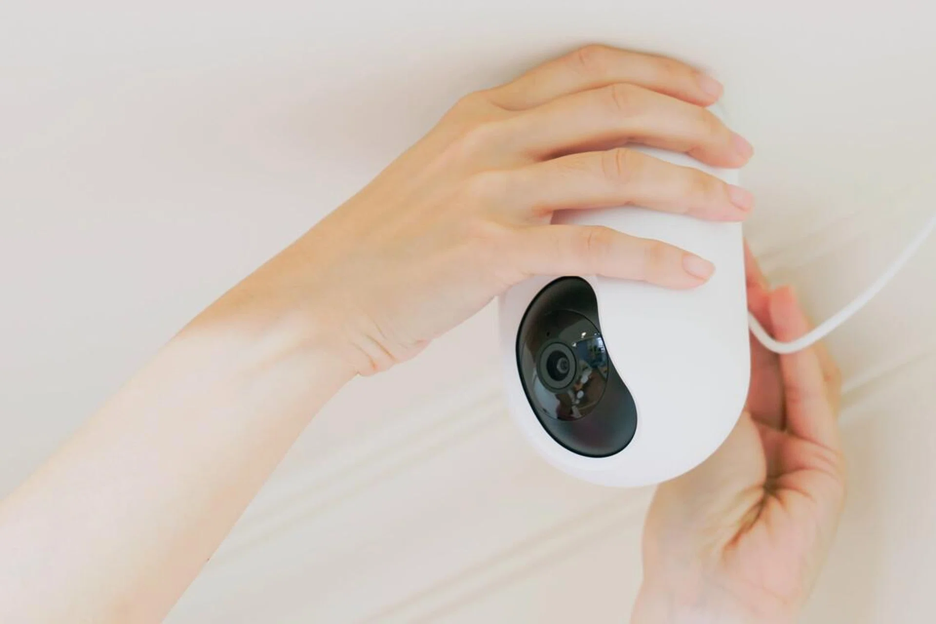 woman is installing surveillance cameras on ceiling at home