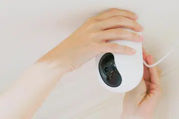 woman is installing surveillance cameras on ceiling at home