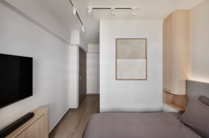 The master bedroom is cocooned by warm wood tones, with an L-shaped wardrobe doubling as a privacy screen.