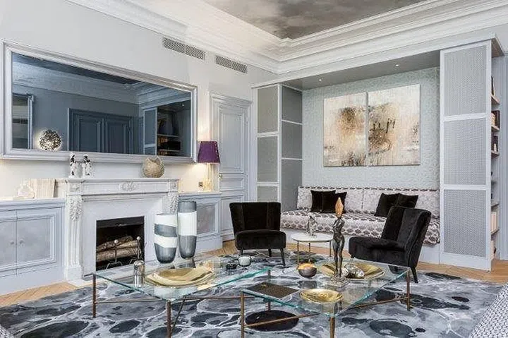 The TV lounge is furnished with oval-shaped glass coffee tables, sleek sofas, as well as wall and pendant lamps that have designs that combine raw materials and precious metals. 