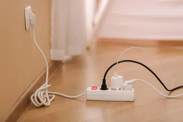 White cable connector for overloaded power boards at home. Close up focus at a plug foreground.