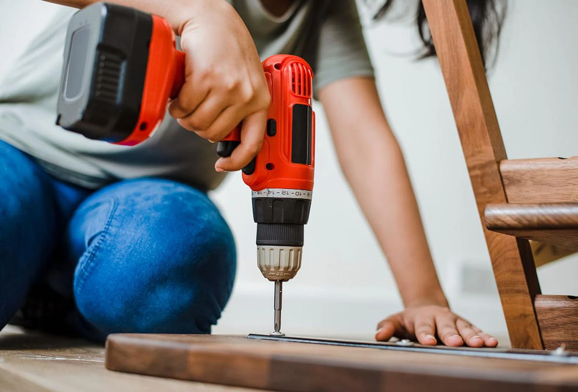 woman using a hand drill to assemble wooden table