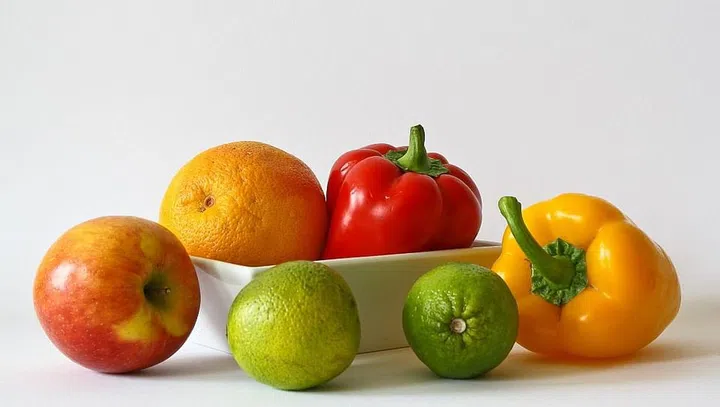 Apple, oranges, peppers, and limes set against a white background.