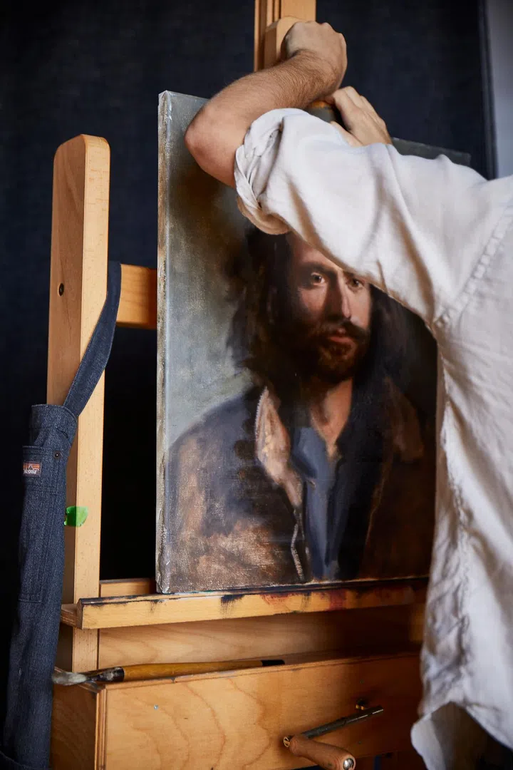 Young artist William Rushton handling a painting of his on an easel in his home and creative studio in a 1918 warehouse in downtown Birmingham, Alabama, restored by architect Paul Bates. Credit: Brie Williams