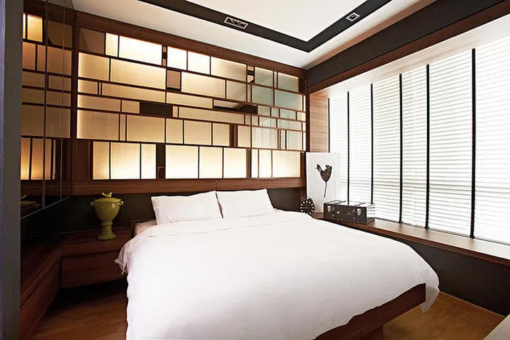 The designer eschews bedside lamps for a lighting feature wall that's practical and good looking. Green pot, clock and suitcase, all from Egg3.