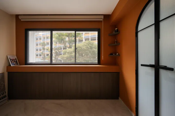 Built-in cabinetry beneath the window creates a calm prayer nook, with warm terracotta walls continuing the suite’s earthy palette.