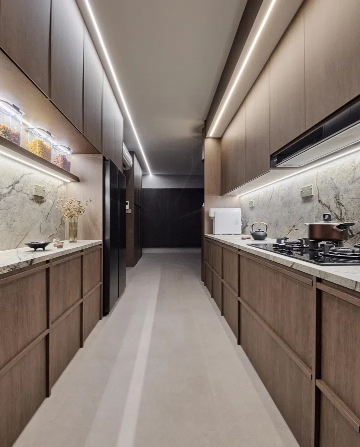 A functional yet elegant kitchen with deep wood-toned cabinetry and veined stone countertop.