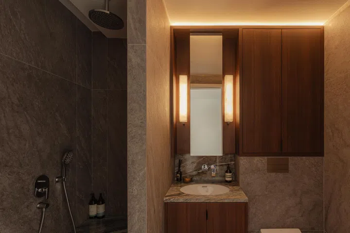 In the bathroom, dark stone and timber cabinetry create a warm, cocooning ambience.