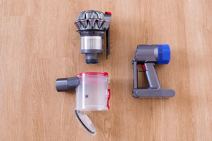 Dyson V8 Fluffy soft roller cleaner head, as well as the main canister, disassembled and displayed on the floor.