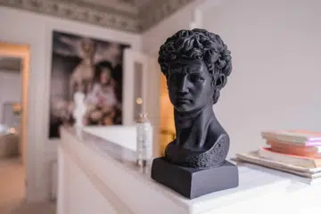 A black bust sculpture of a Grecian man set on a console home bar in an apartment. Photo by Pexels Sami Abdullah