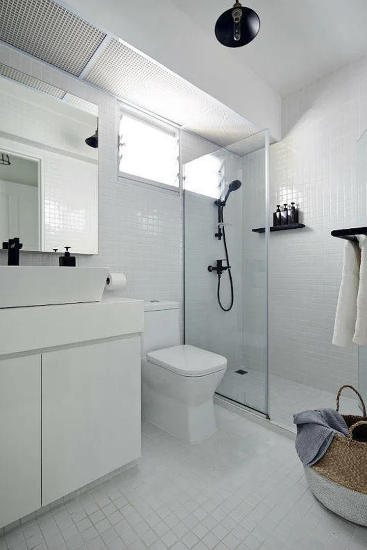 Black fittings, fixtures and accessories provide marked contrast against the otherwise all-white master bathroom in this Choa Chu Kang 5-room HDB.