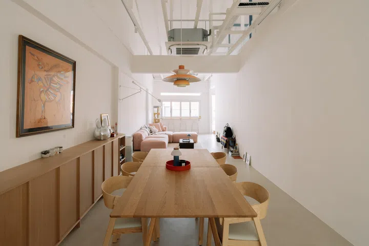 An eight-seater solid oak dining table sits beneath a Louis Poulsen pendant, while bespoke oak cabinetry, exposed roof trusses and a soaring double-volume ceiling lend the open-plan living space an airy sense of openness.