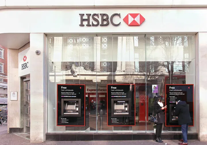 February 08: HSBC bank branch with glass wall on Oxford Street in London, UK - February 08, 2015; HSBC bank branch with people outside on street using ATM machines. Photo 123RF